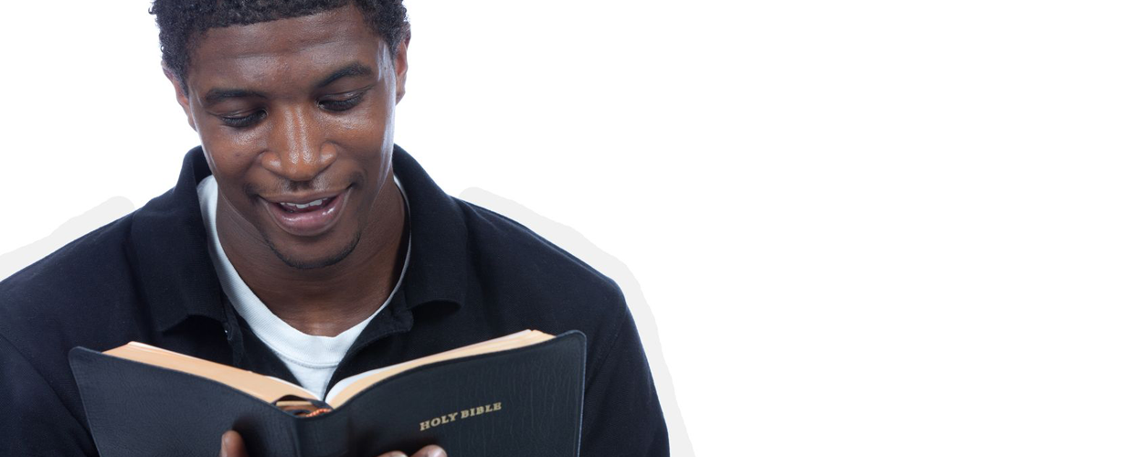 A person reading a book with a slightly smiling expression, indoors, white background.