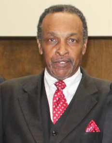 Man in suit and red patterned tie, looking at the camera.
