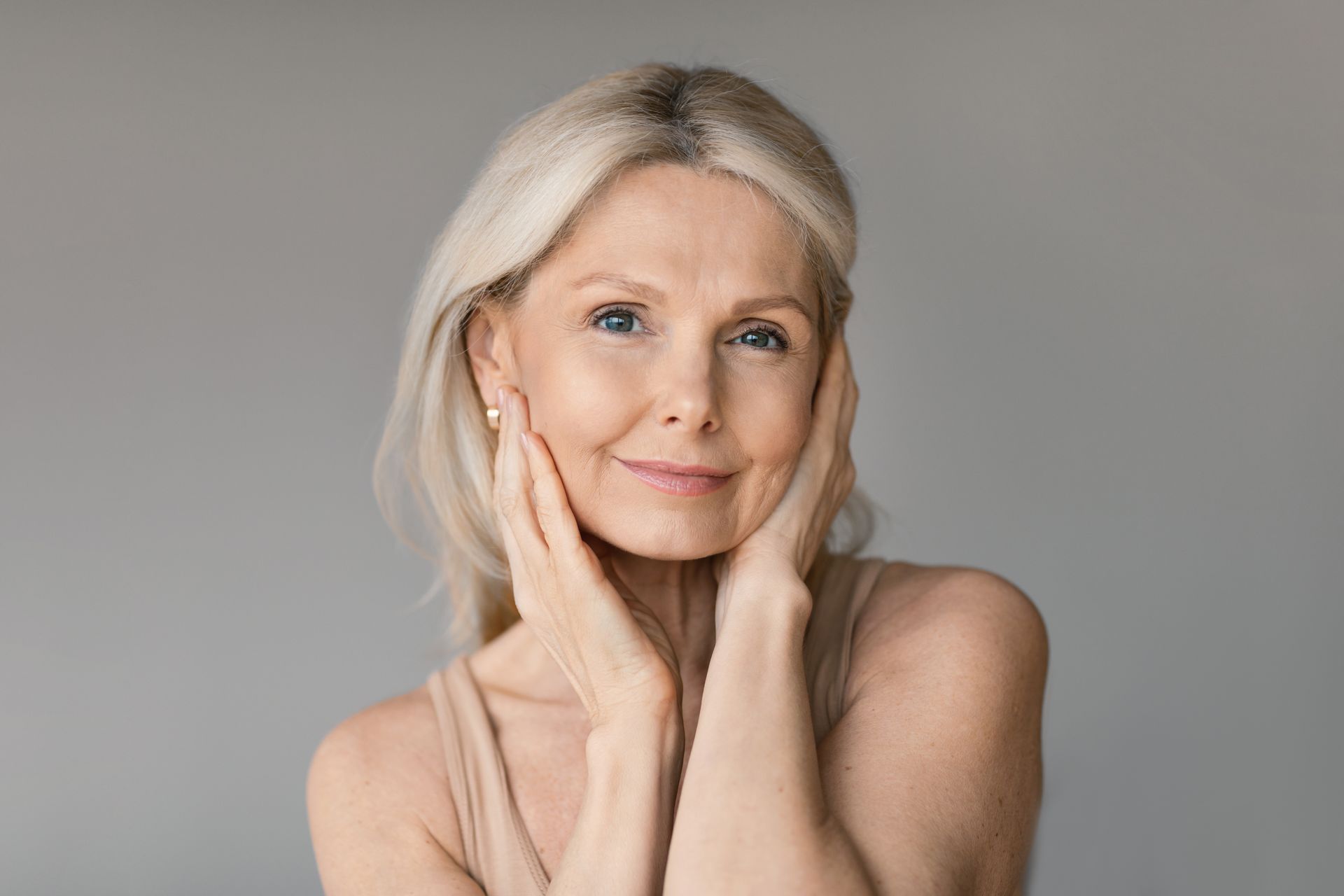The woman is smiling and holding her hand to her face.