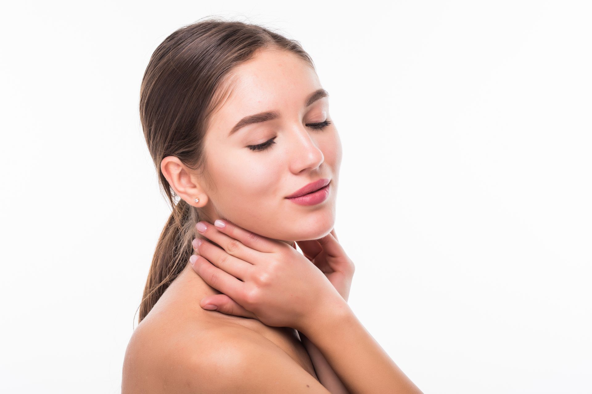 A beautiful woman with her closed eyes has her hands placed at the side of her neck 