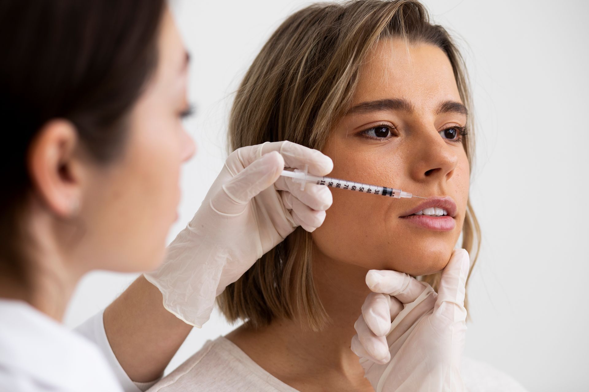 A woman is getting a dermal filler injection in her lip.