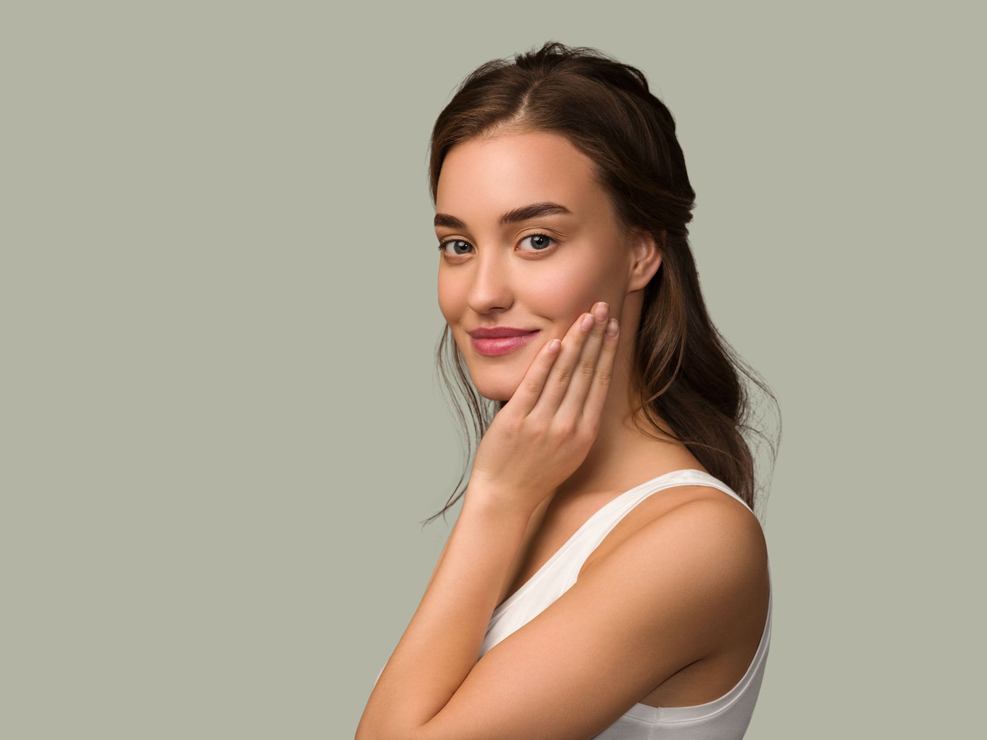 A woman is touching her face with her hand and smiling.
