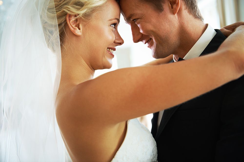 A bride and groom are dancing and looking at each other.