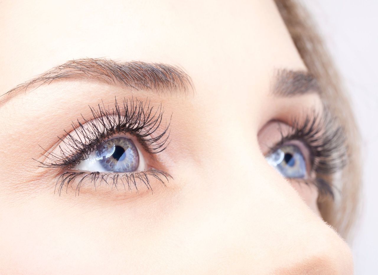 A close up of a woman's blue eyes with long eyelashes.