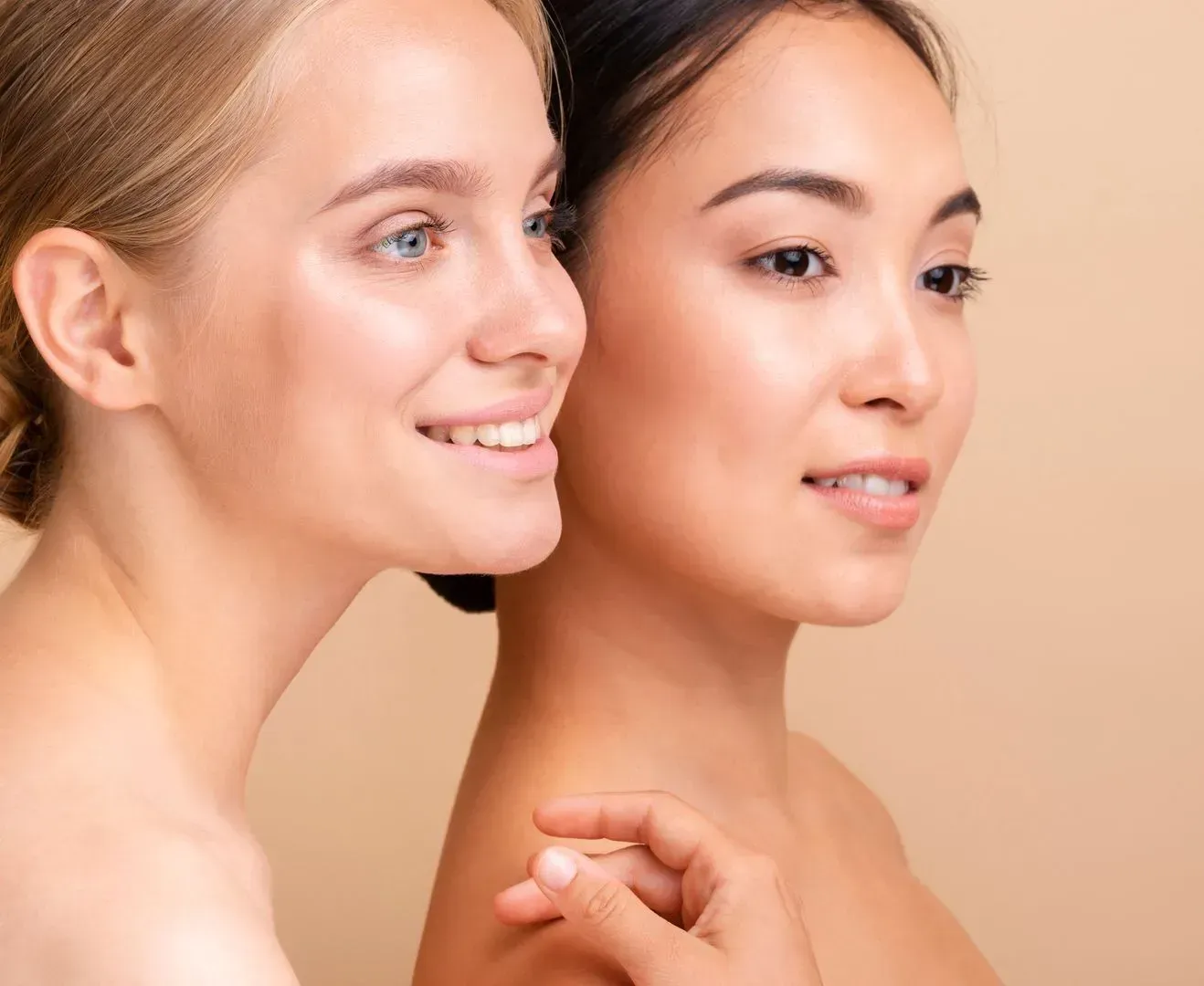 Two beautiful young women are standing next to each other and smiling.