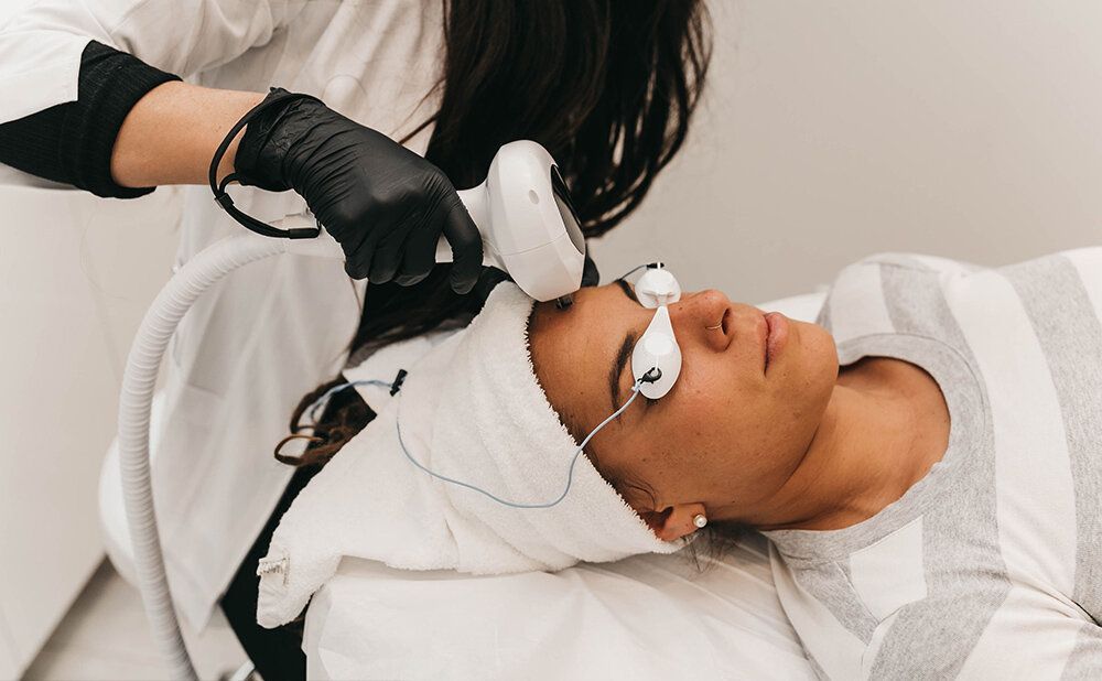 A woman is getting a laser treatment on her face.