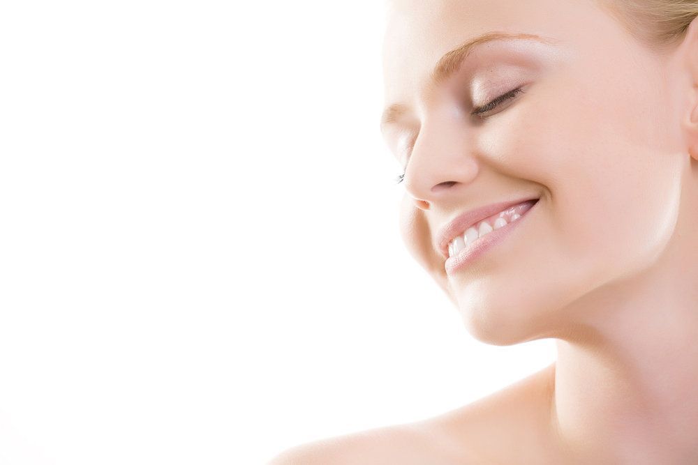 A close up of a woman 's face smiling with her eyes closed.