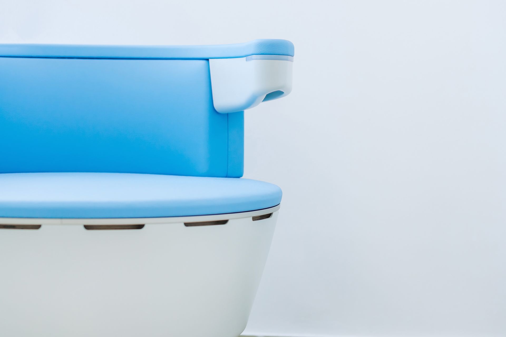 A blue and white toilet is sitting in front of a white wall.