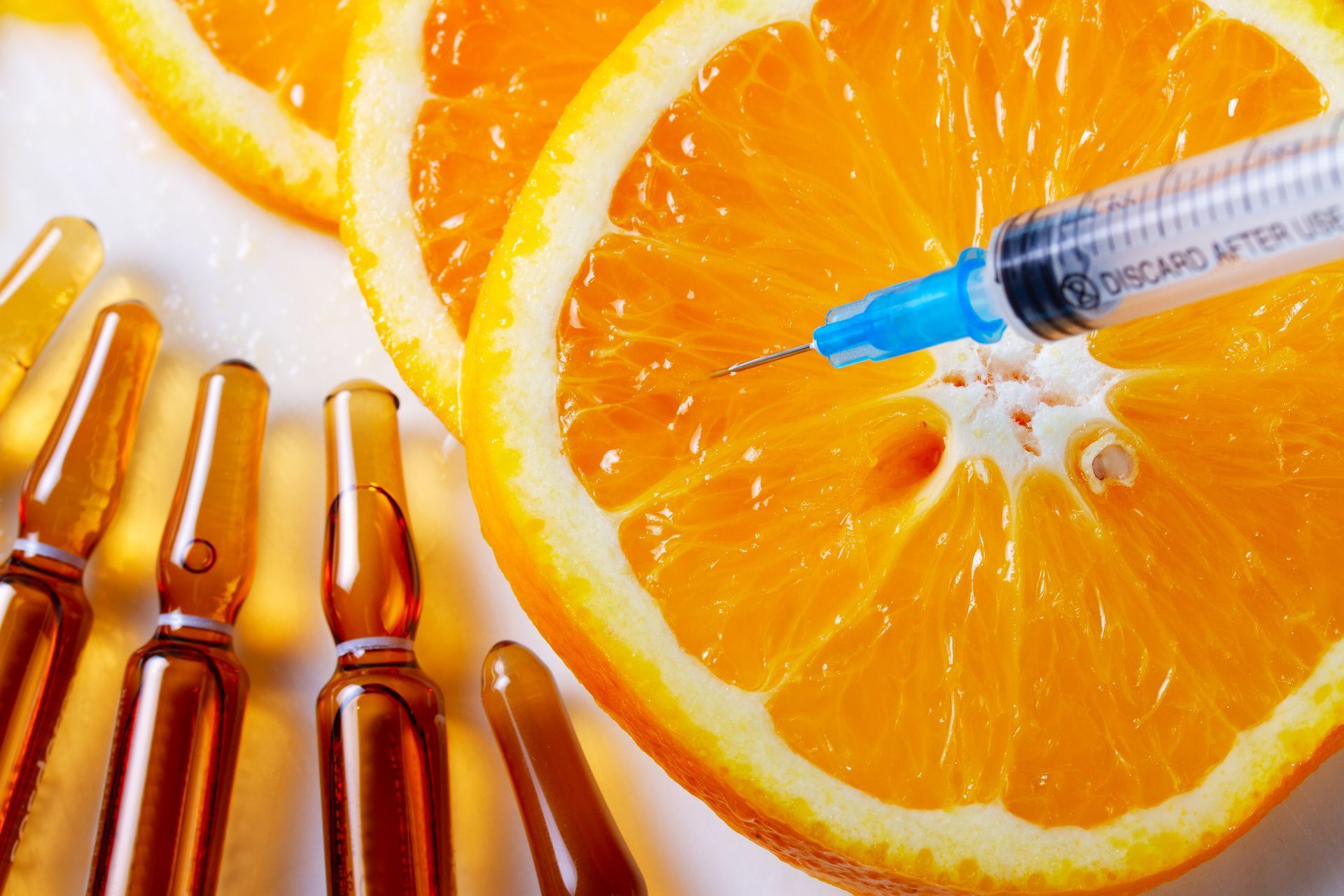 A syringe is being inserted into an orange slice.
