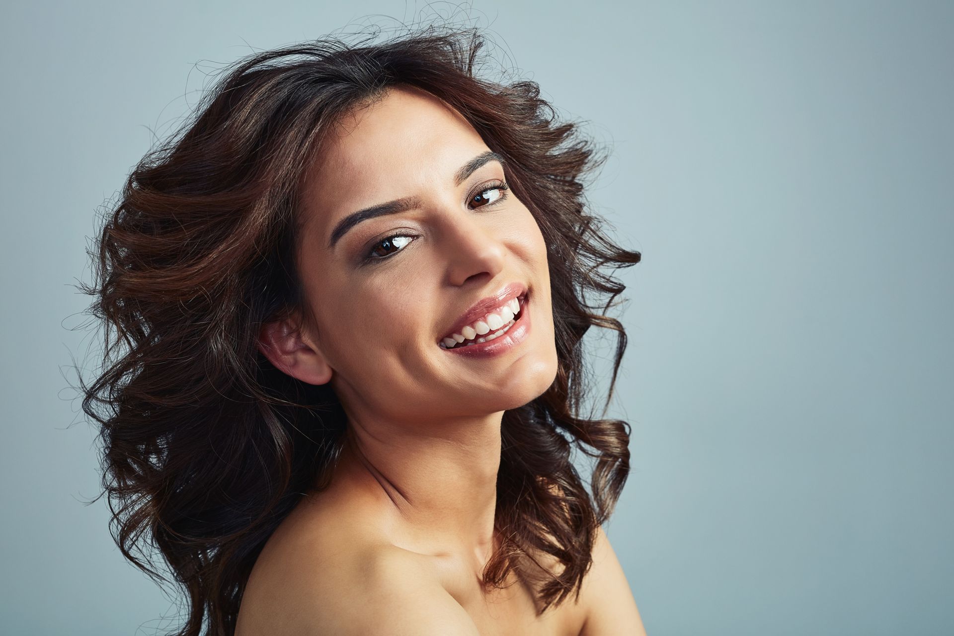 A woman with curly hair is smiling and looking at the camera.