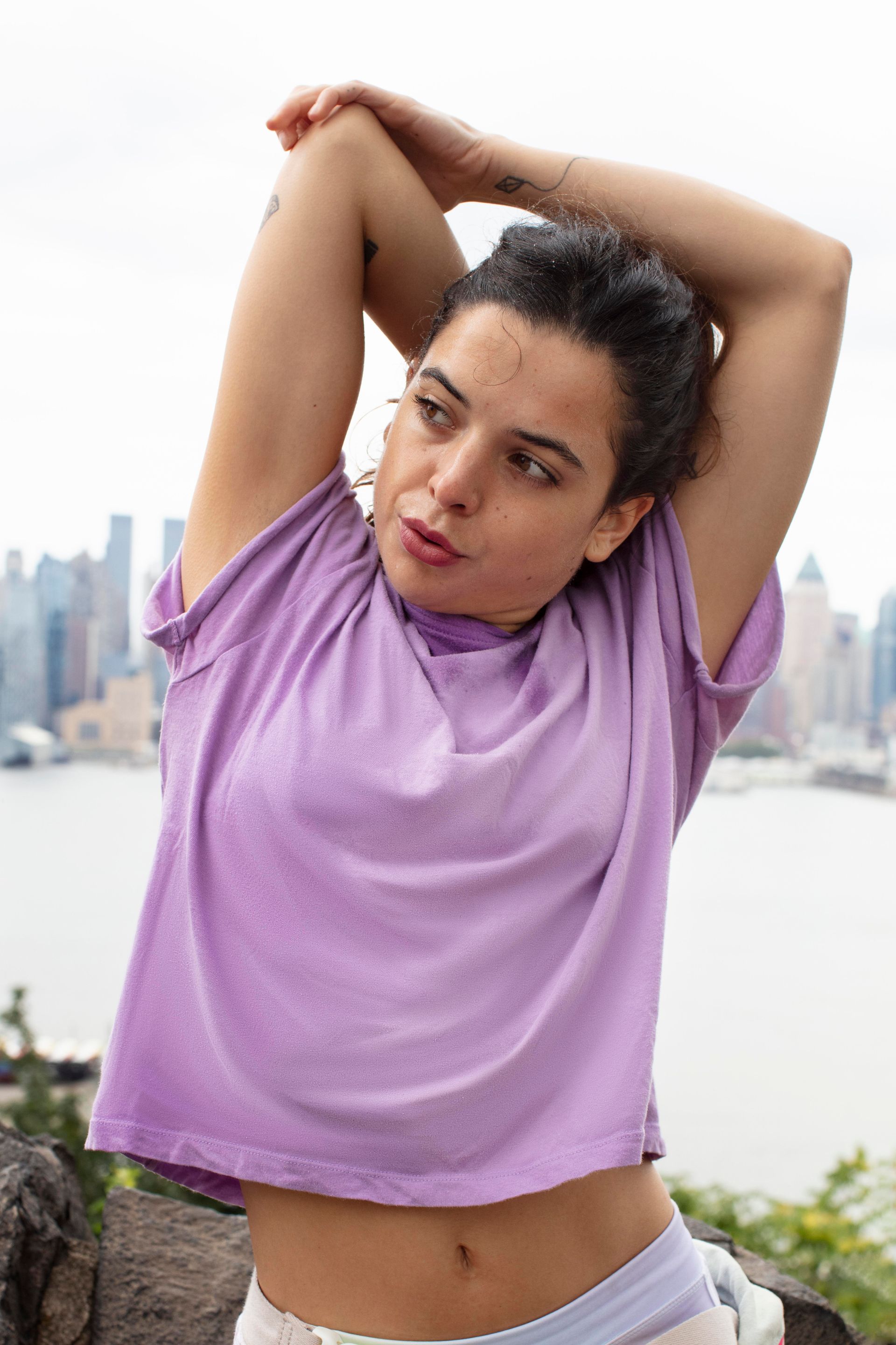 A woman in a purple t-shirt is stretching her arms.