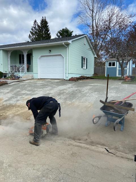 A man is working on a driveway in front of a house.