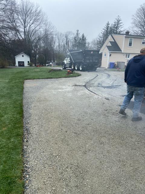 Two men are walking down a driveway in front of a house.