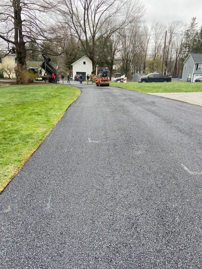 A asphalt driveway is being built in a residential neighborhood.