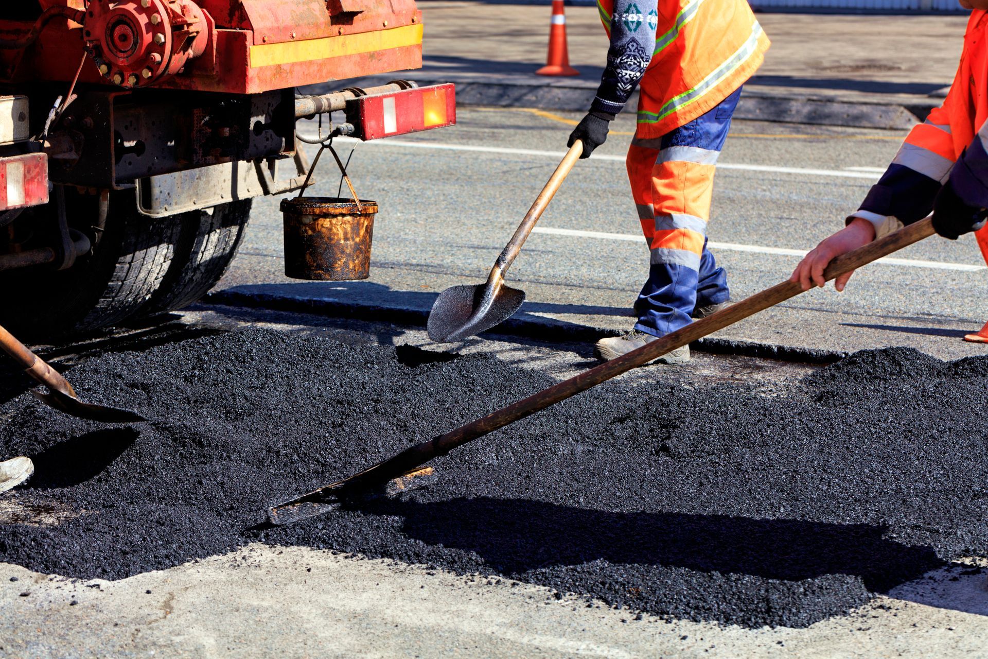 Asphalt paving team working to apply and level fresh asphalt for road repair and construction