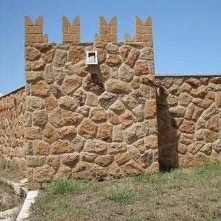 Facciata di immobile con merli costruita con tufo