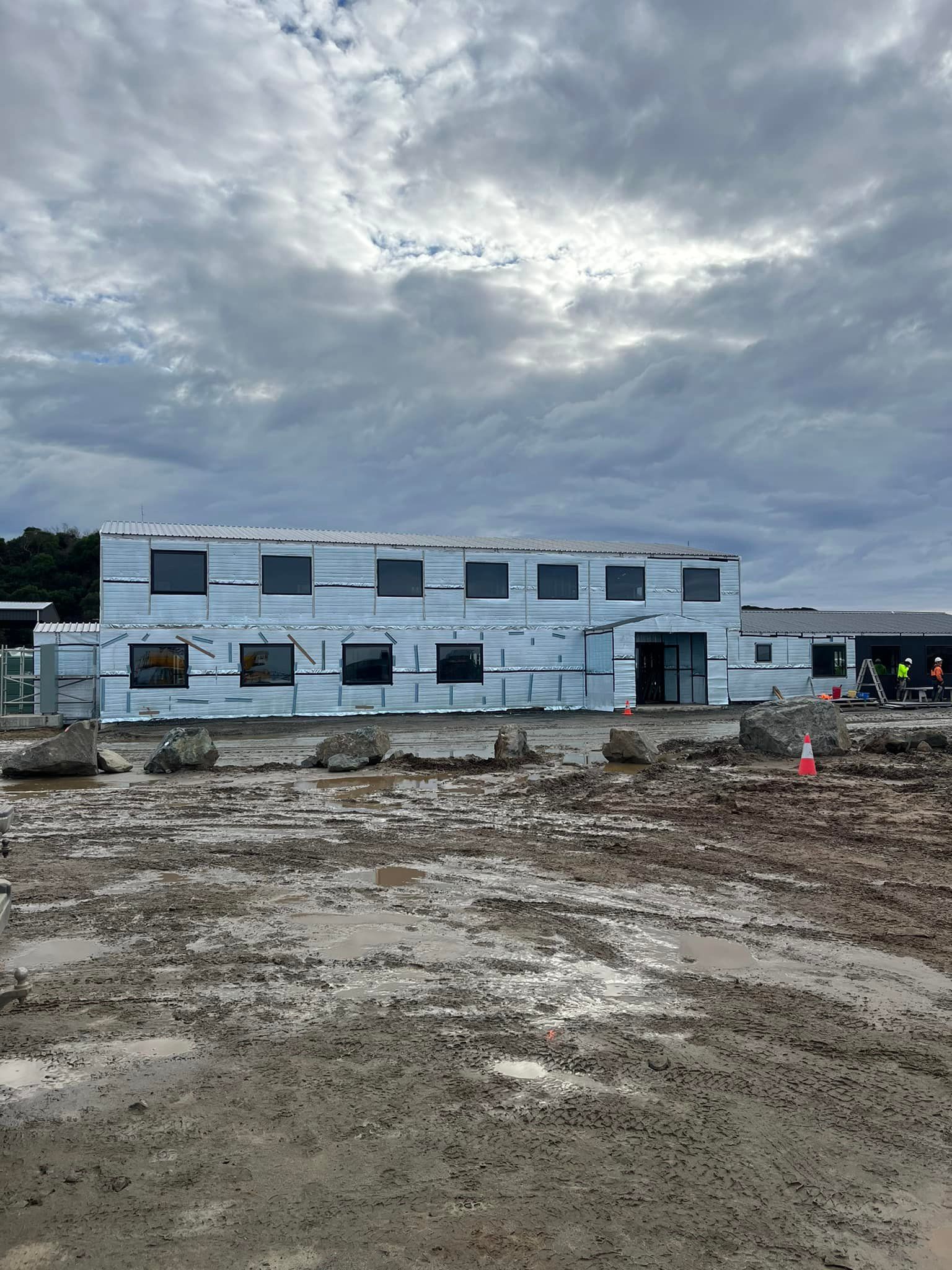 Blue metal framing of a building's interior under construction, with concrete floor and exposed wiring.