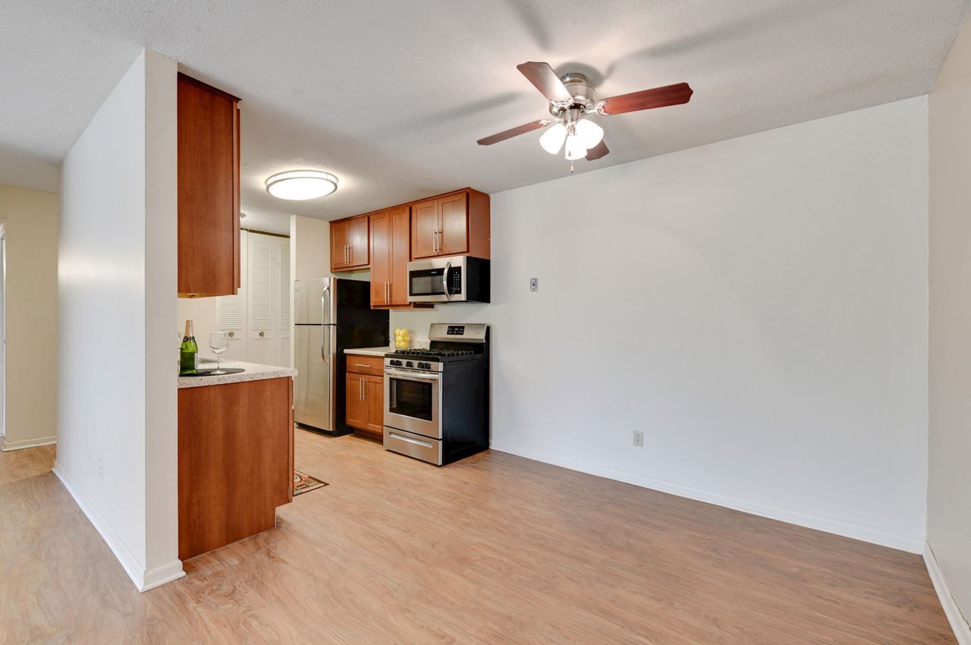 Kitchen with wood cabinets, stainless steel appliances, and ceiling fan in a brightly lit room at Manor Royal in Plymouth, MN.