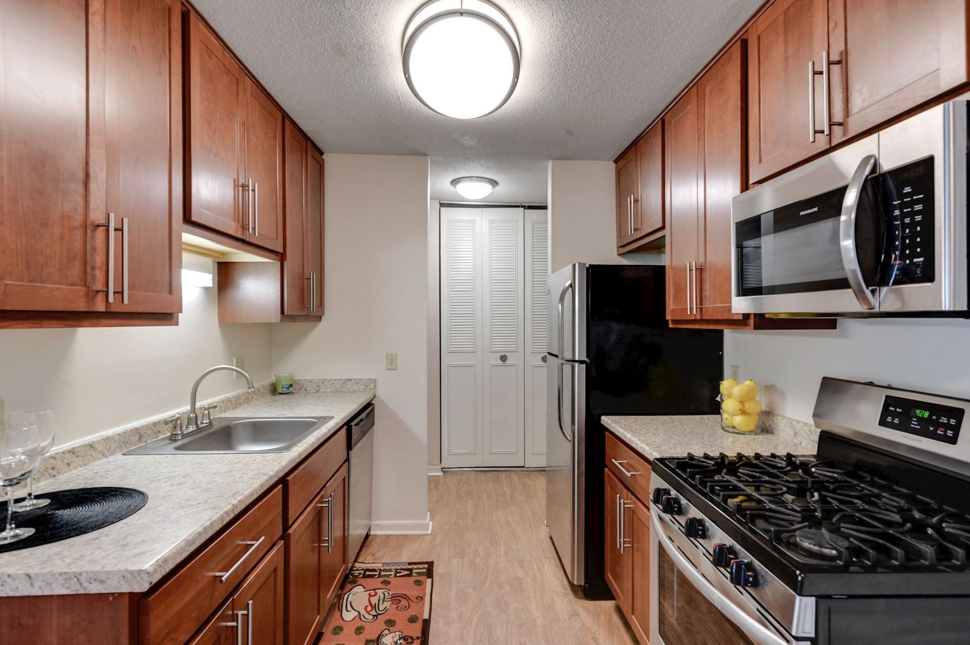 Narrow kitchen with wood cabinets, stainless steel appliances, and light countertops at Manor Royal in Plymouth, MN.