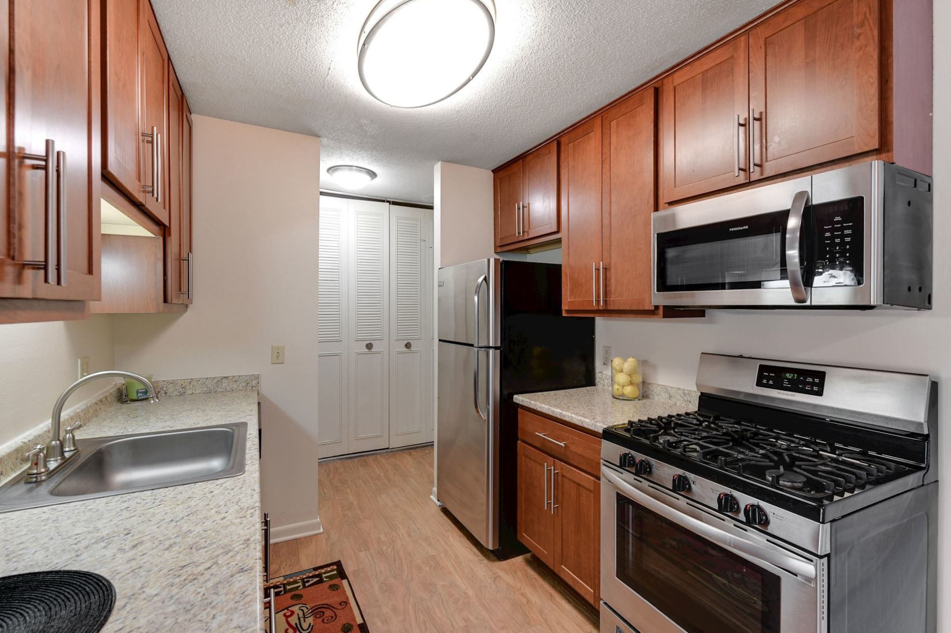 Small kitchen with wooden cabinets, stainless steel appliances, and a light countertop.