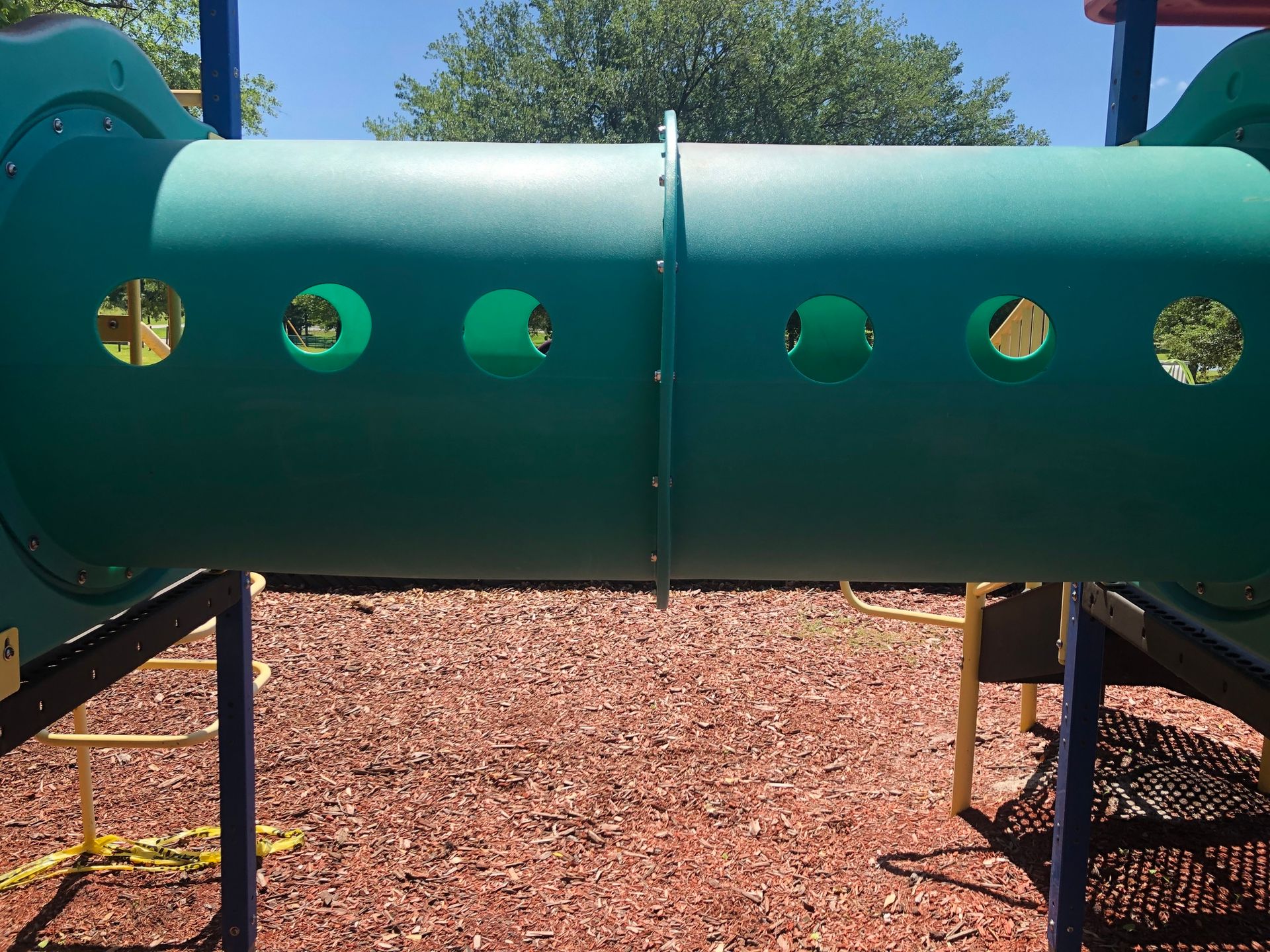 A green playground tunnel with holes in it