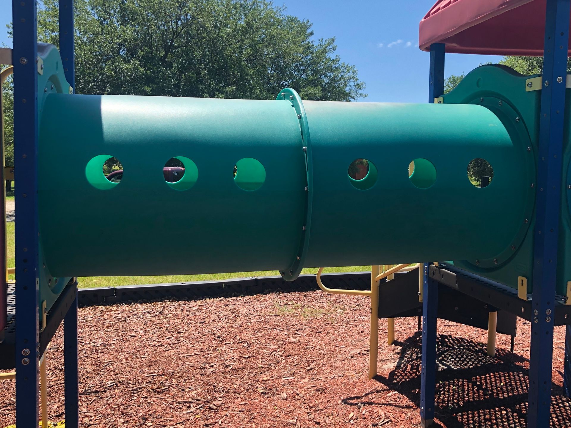 A green tunnel in a playground with holes in it