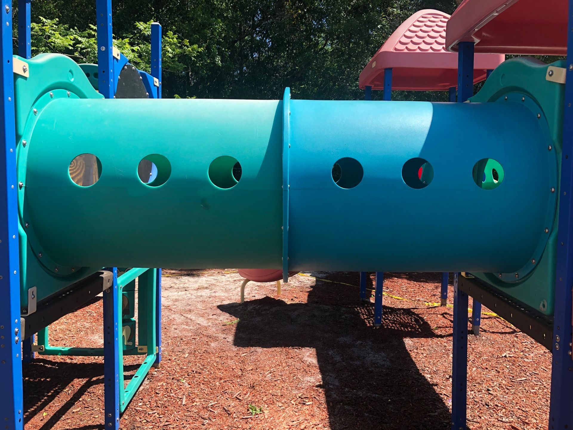 A blue tunnel in a playground with holes in it