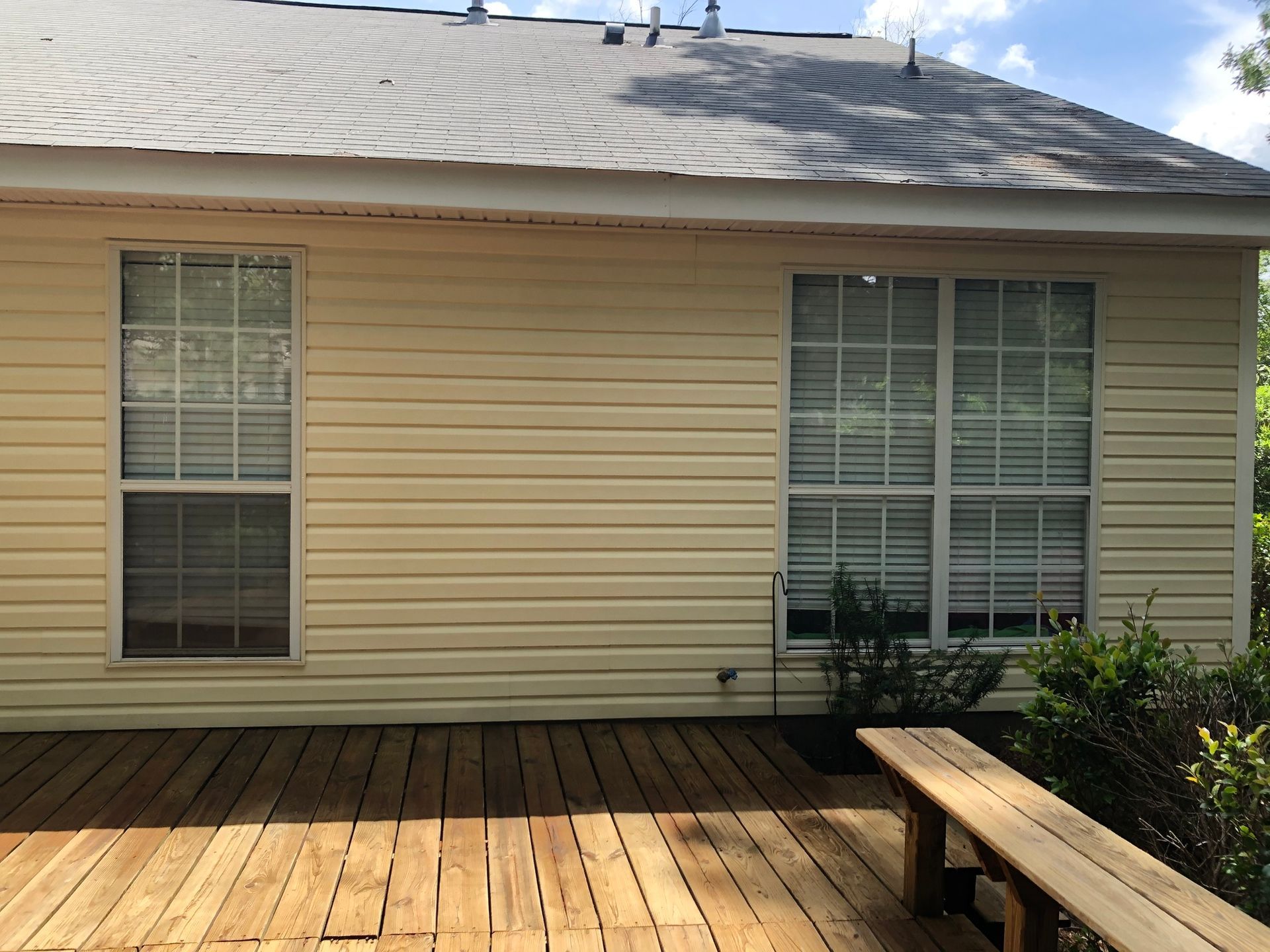 A house with a wooden deck and a bench in front of it
