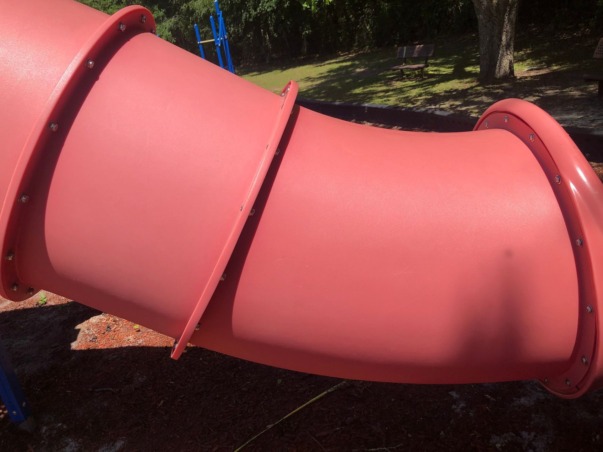 A red slide in a park with trees in the background