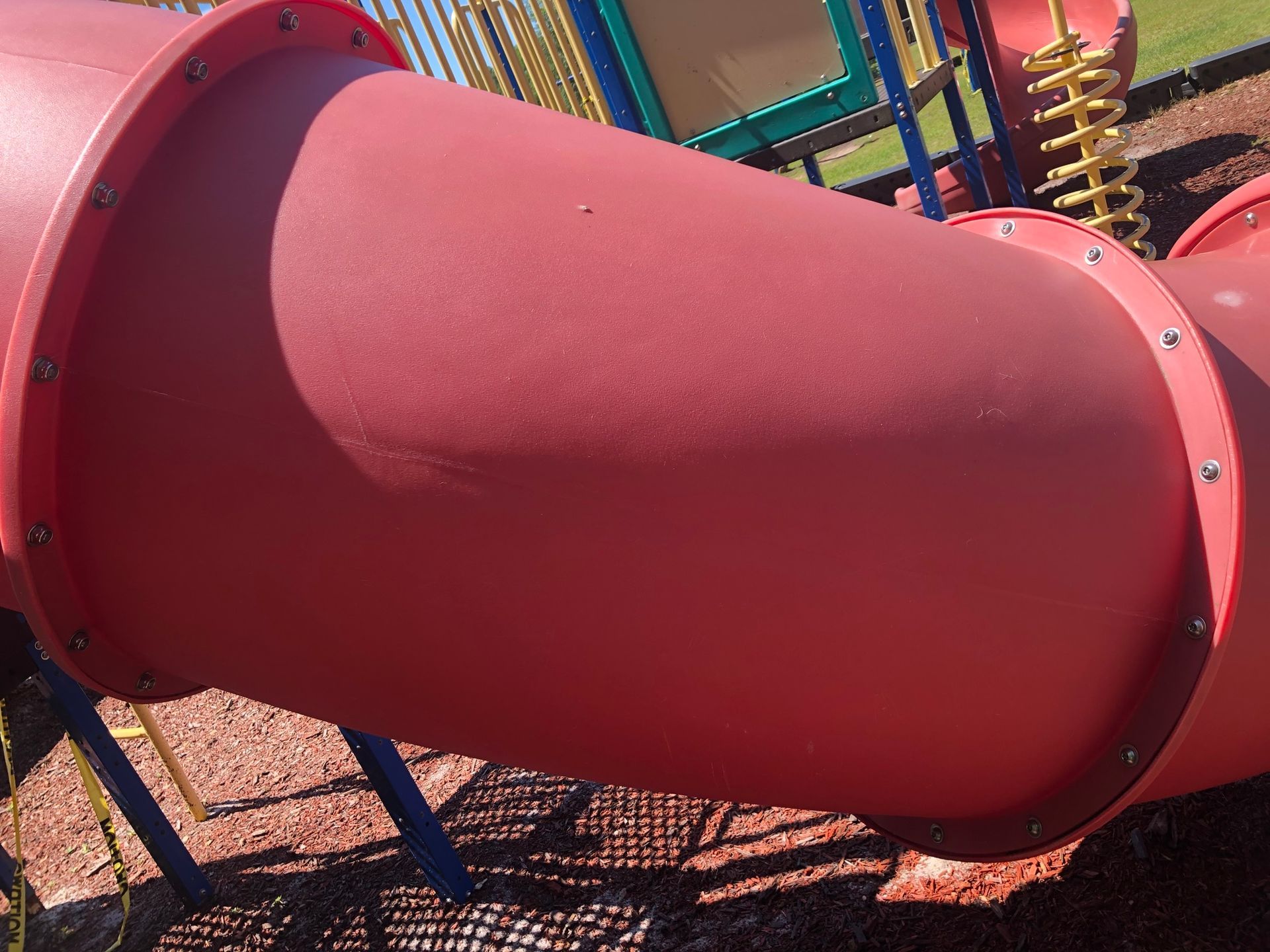 A red tube is going down a playground slide