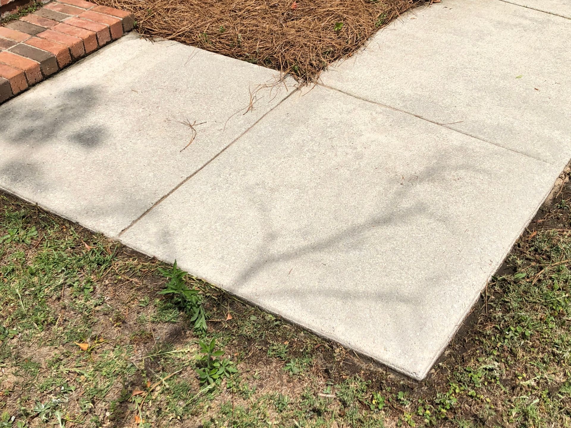 A concrete sidewalk with a brick walkway in the background.