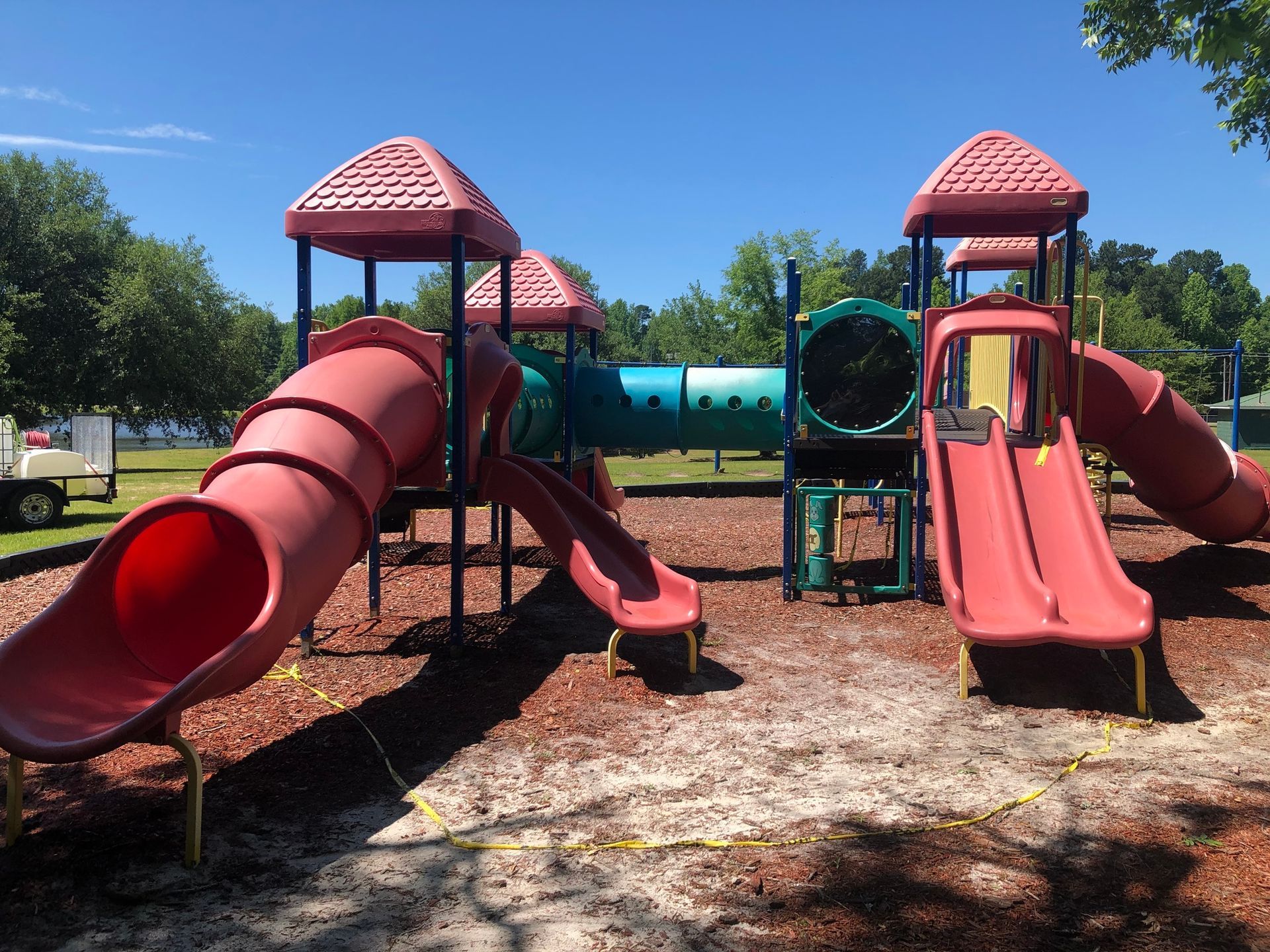 A playground with red slides and a tunnel