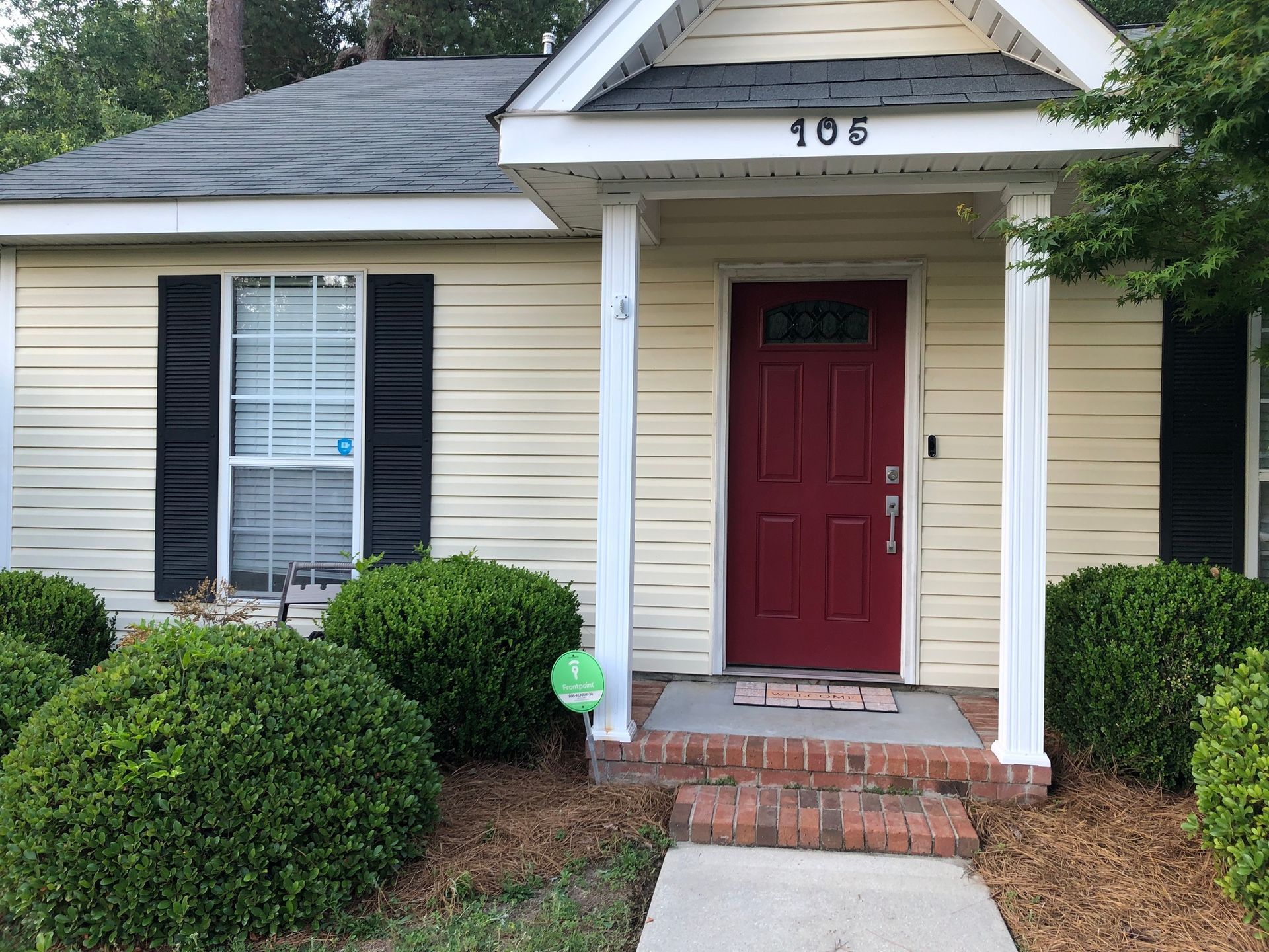 A yellow house with a red door and black shutters