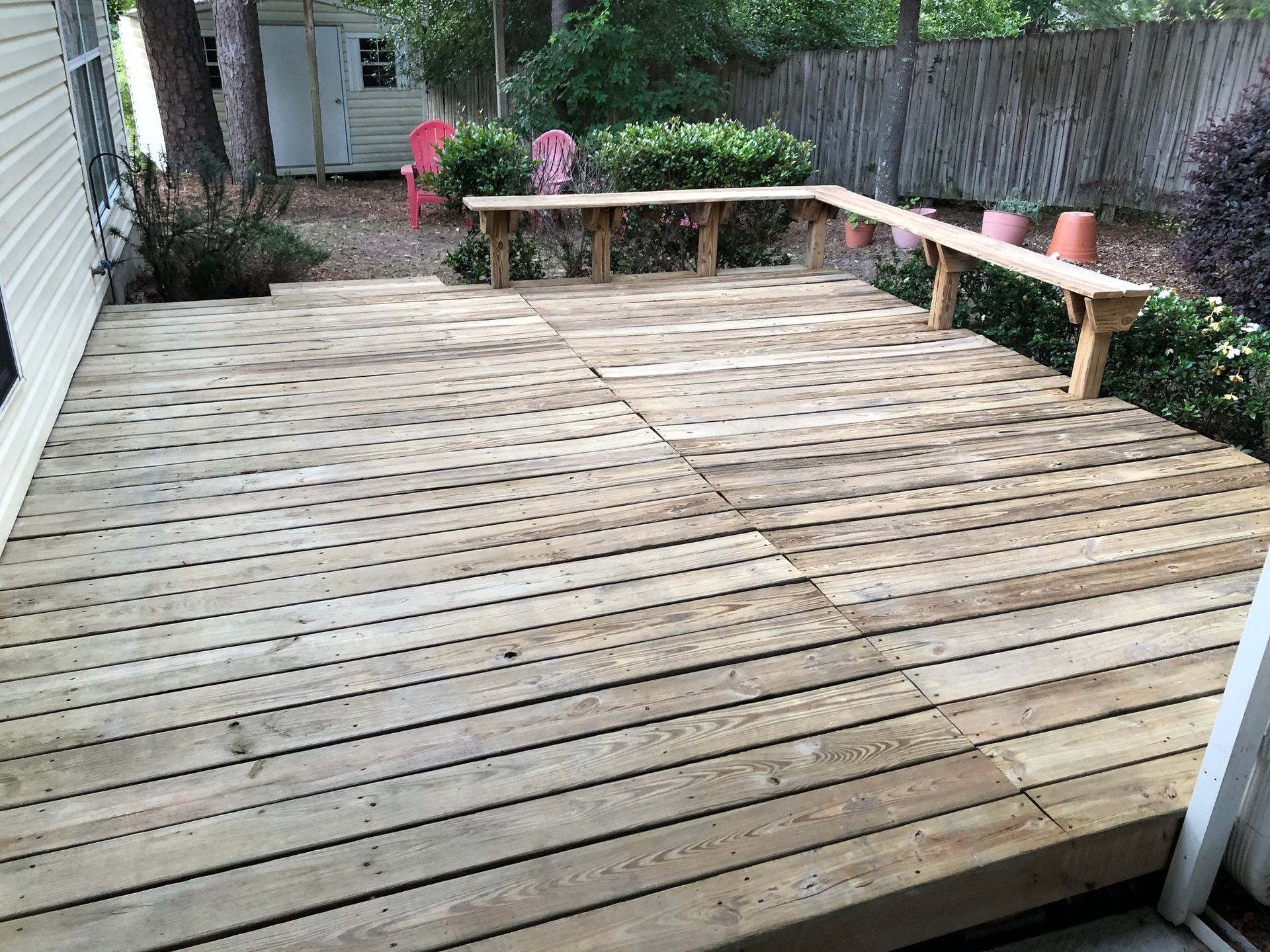 A wooden deck with a bench on the side of it.