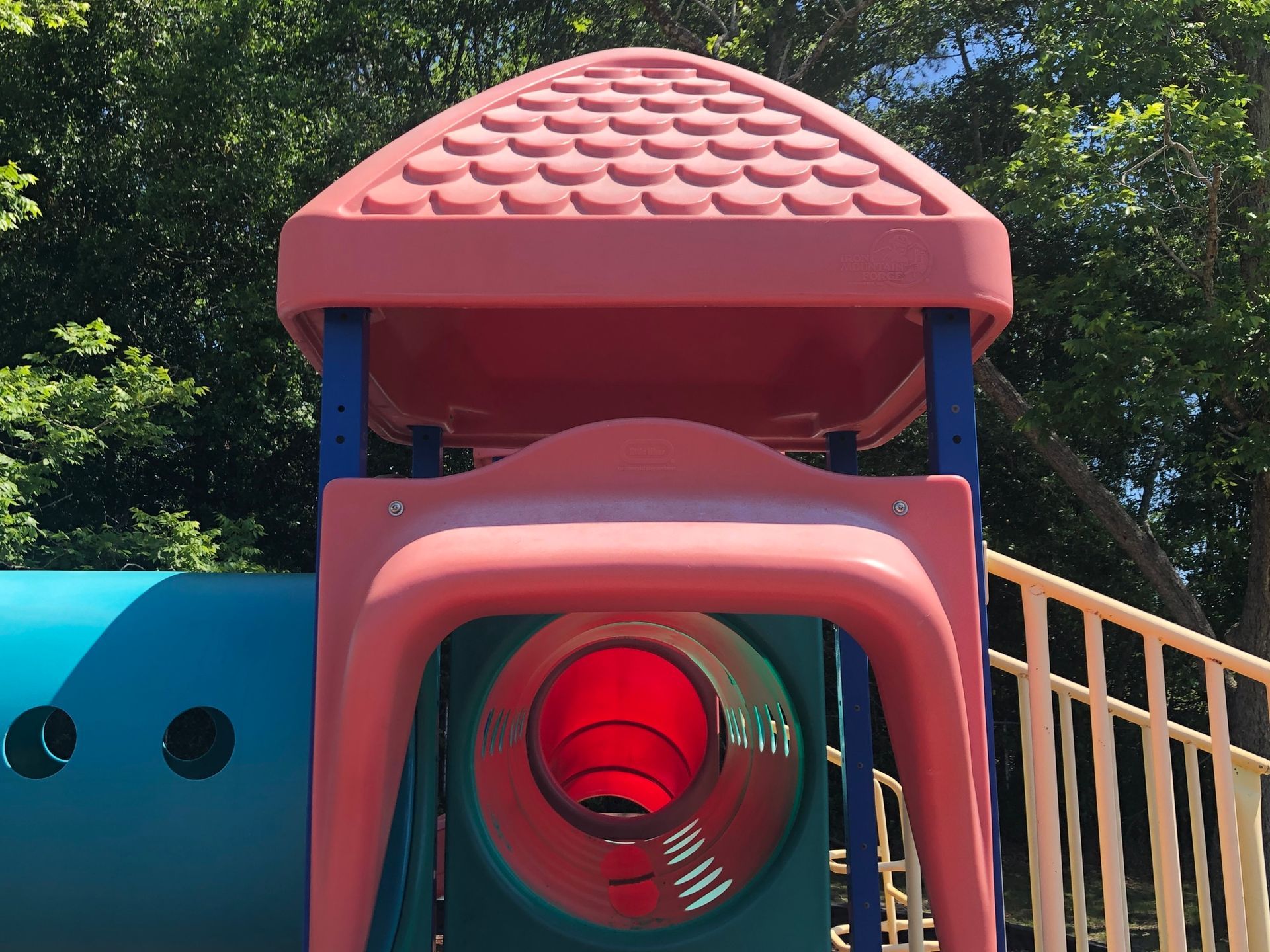 A playground with a red tunnel and a pink roof