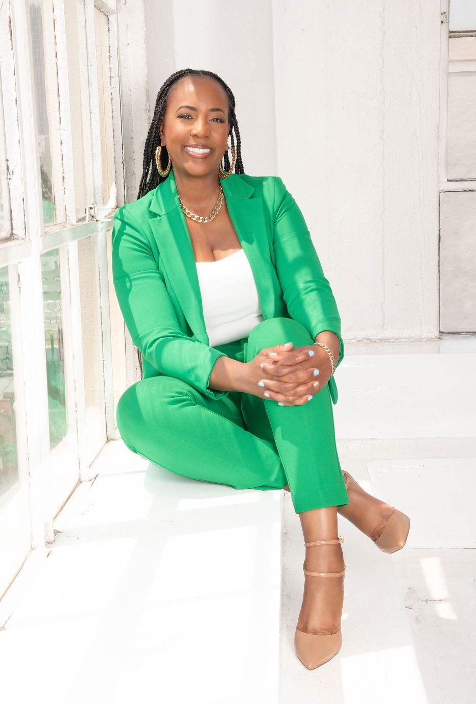 A woman in a green suit is sitting on a white box.