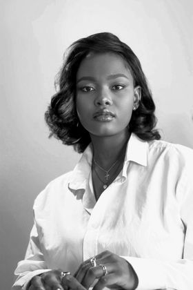 Woman with wavy hair and a white collared shirt, looking directly at the camera.
