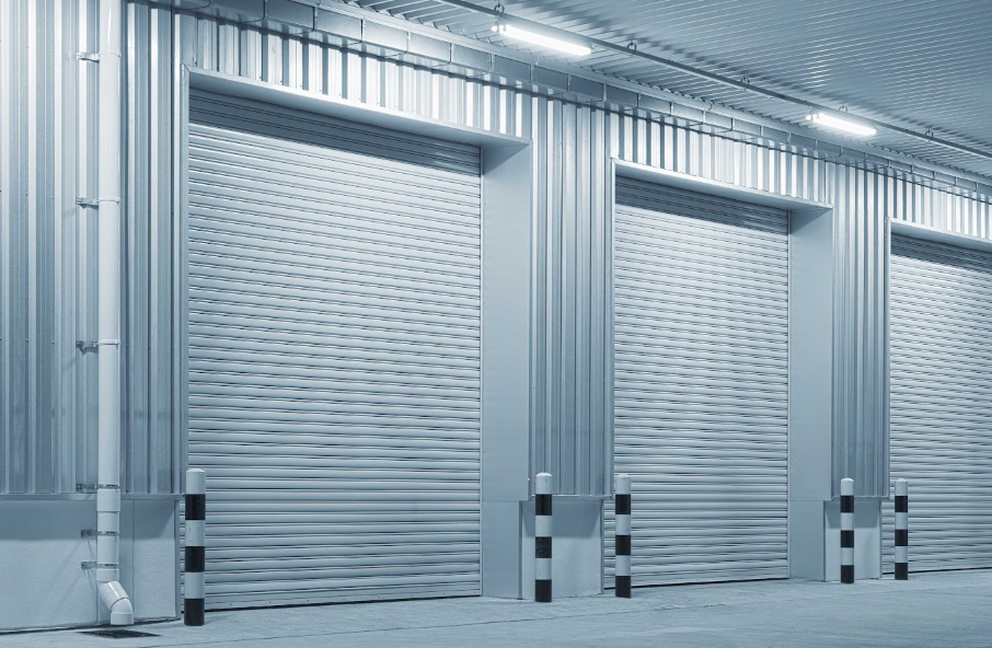 Three closed metal roller shutter doors on an industrial building, blue-gray tones.
