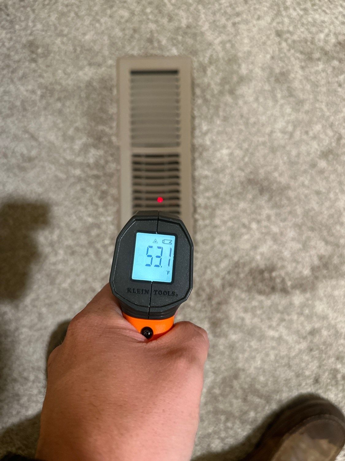 Person using a thermometer to measure the temperature of a vent; the temperature reading is 53 degrees.