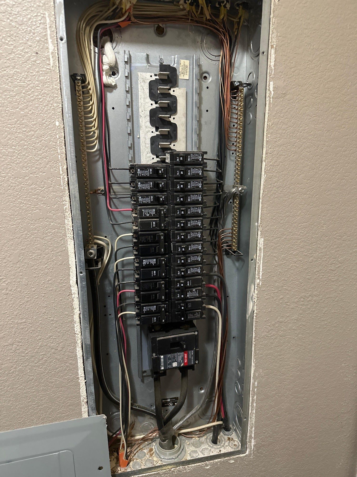 Electrical panel with various breakers and wiring inside a wall, gray and black colors.