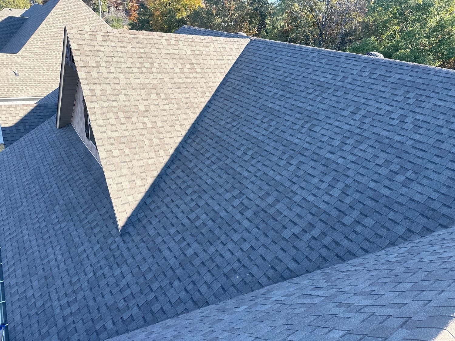 Gray asphalt shingle roof on a residential building with multiple angles and gables.