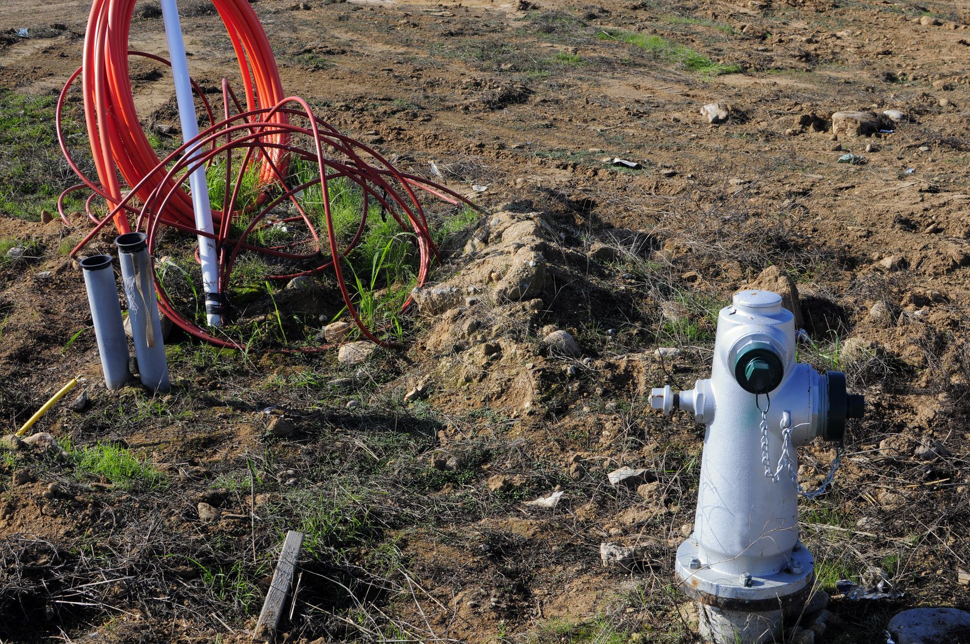 Hand holding a white TDS meter in a glass of clear water against a dark background.