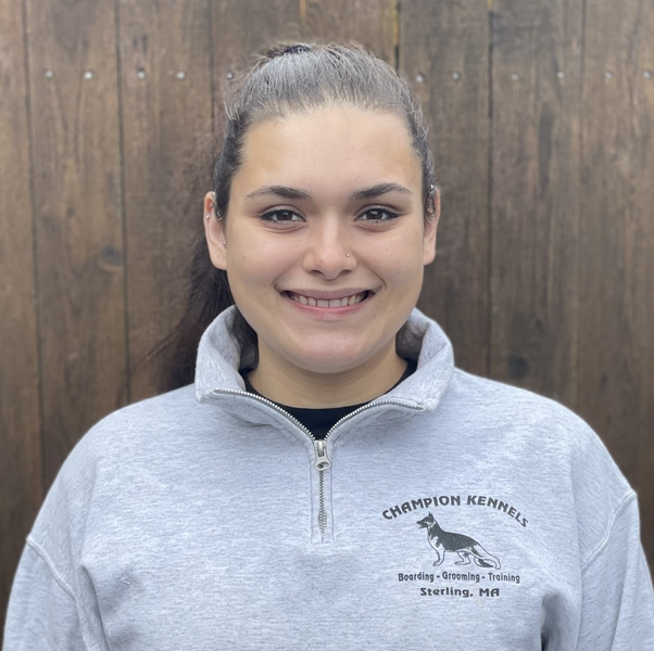 A woman wearing a champion kennels sweatshirt smiles for the camera.