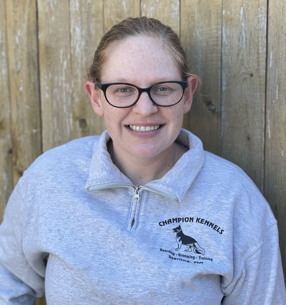 A woman wearing glasses and a champion kennels sweatshirt.