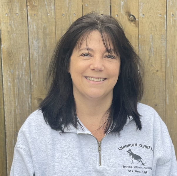 A woman wearing a champion kennels sweatshirt smiles for the camera.