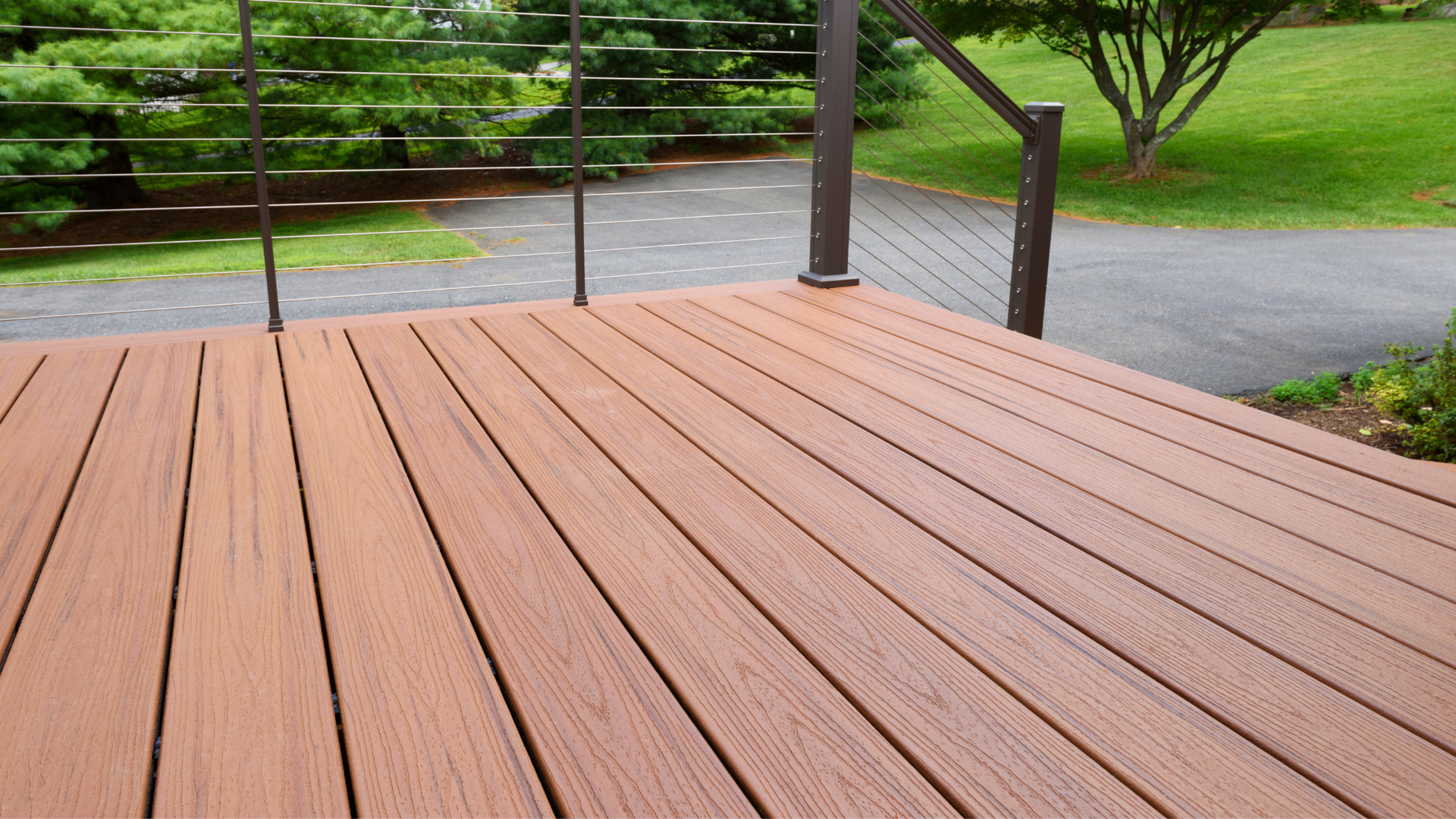 Composite deck with a beautiful wood design, surrounded by lush green trees.