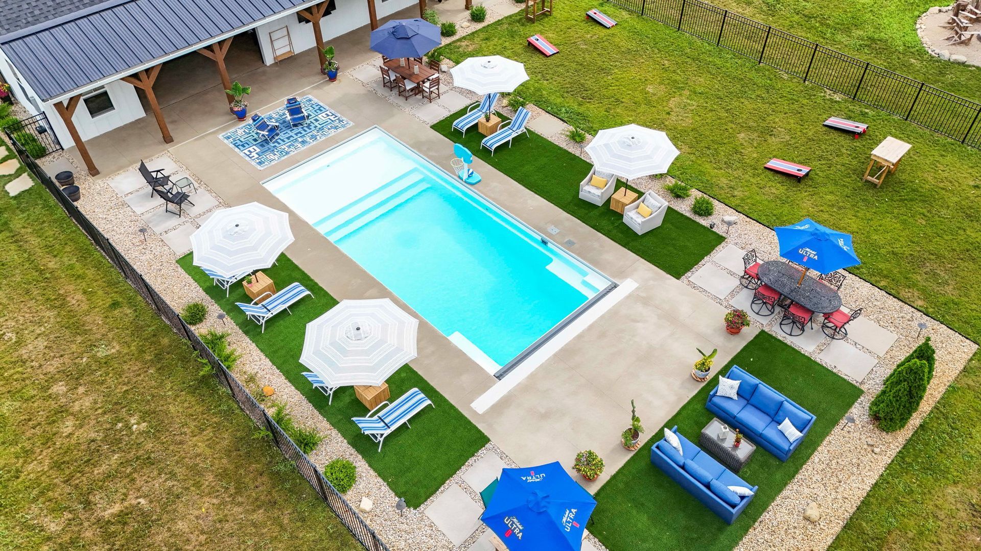 An outdoor swimming pool with lounge chairs and a modern apartment building in the background on a sunny day.