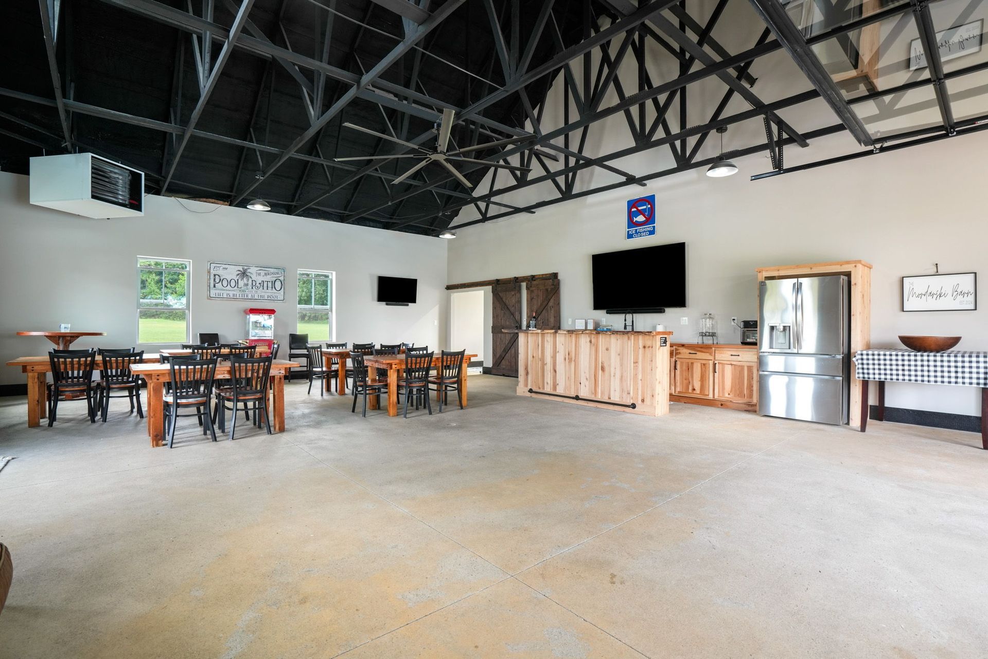 Outdoor kitchen area with grills, sink, TV, and seating near a pool.