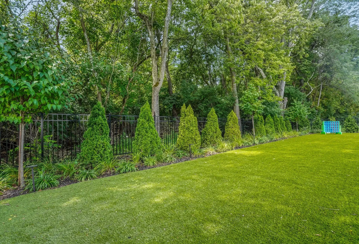 Artificial Turf backyard featuring lush green grass and tall trees.