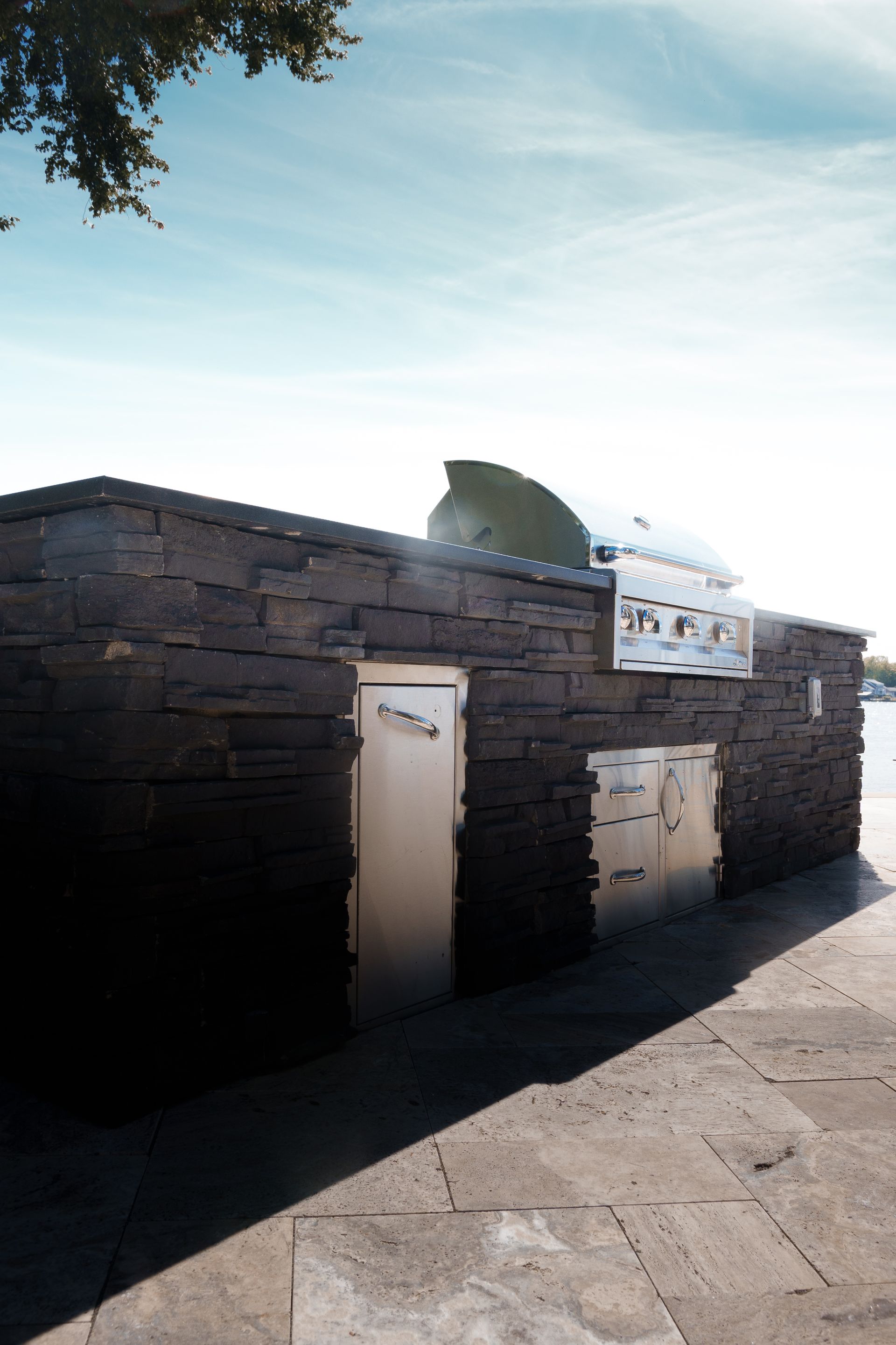 Stone building with metal doors and signage, casting a long shadow under a bright sky.